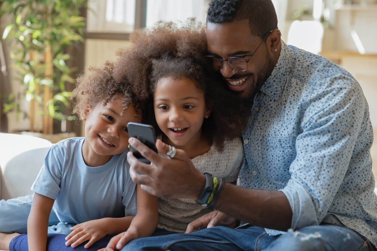 Happy daddy and excited sibling kids watching amazing content